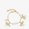 Pulsera con múltiples dijes en forma de lazo Pulsera de metal dorado con dijes, lazos y perlas Pulsera con múltiples dijes en forma de lazo Pulsera de metal dorado con dijes, lazos y perlas
