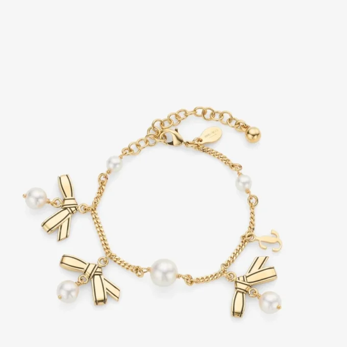 Pulsera con múltiples dijes en forma de lazo Pulsera de metal dorado con dijes, lazos y perlas Pulsera con múltiples dijes en forma de lazo Pulsera de metal dorado con dijes, lazos y perlas